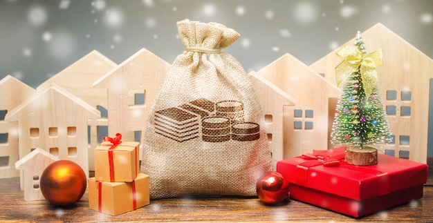Bolsa de dinero, casas de madera, árbol de Navidad y regalos.