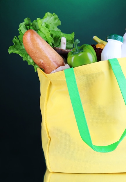 Foto bolsa ecológica con compras sobre fondo verde oscuro