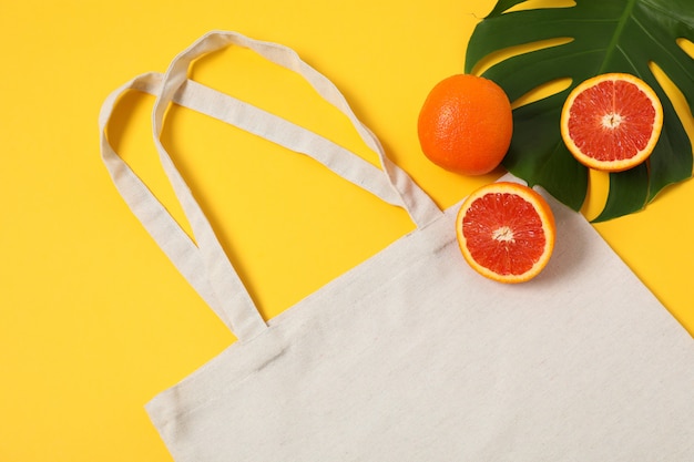 Bolsa ecológica, hoja de palma y naranja sobre fondo de color