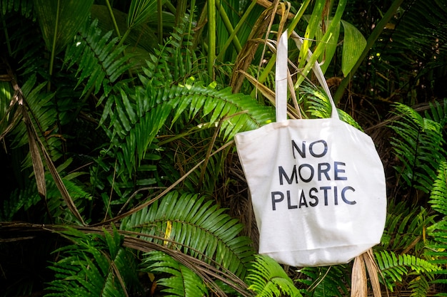 Bolsa ecológica NO MÁS PLÁSTICO en medio de follaje tropical fresco y verde