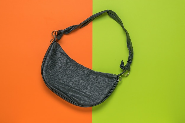 Bolsa feminina elegante em forma de banana em um fundo laranja e verde. a vista do topo.