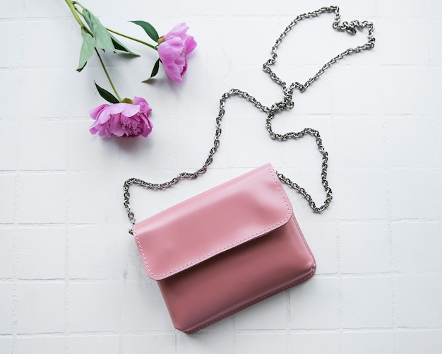 Bolsa feminina feita de couro rosa sobre fundo de ladrilho branco