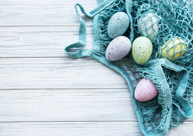 Bolsa de hilo con huevos de Pascua y flor de primavera en la esquina de una mesa de madera rústica