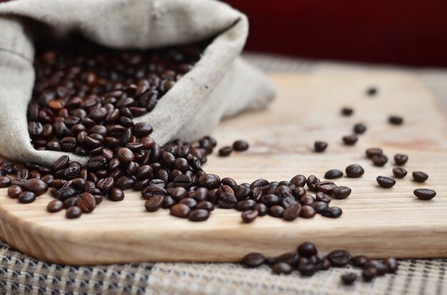 Una bolsa llena de granos de café marrón se encuentra en una superficie de madera