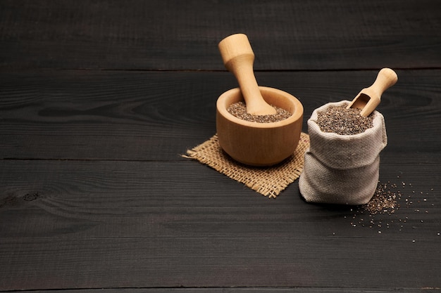 bolsa llena de semillas de chía naturales orgánicas sobre fondo o mesa de madera oscura