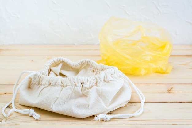 Foto una bolsa de lona abierta vacía con corbatas para comida y una bolsa de plástico sobre un fondo de madera natural.