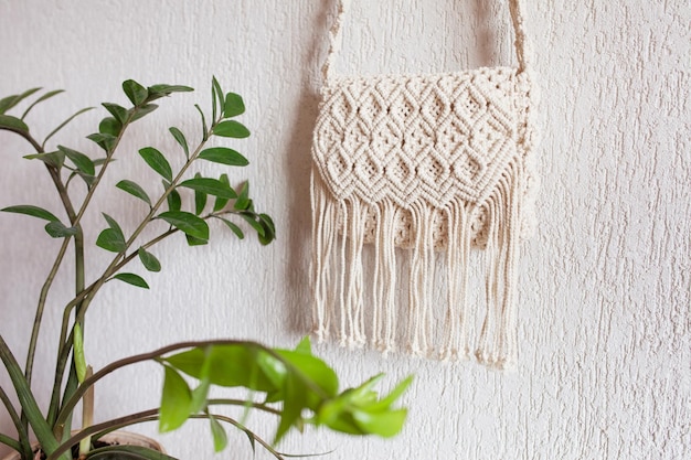 Bolsa de macramé hecha a mano en la pared de luz Bolsa de algodón macramé natural respetuosa con el medio ambiente Hobby tejer macramé hecho a mano Concepto moderno de verano Espacio de copia