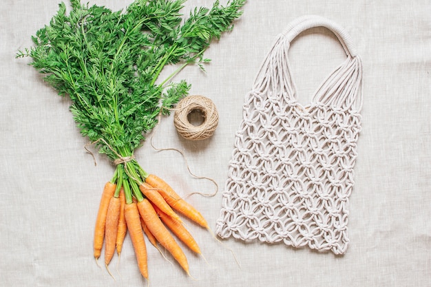 Bolsa de macramé hecha a mano con zanahorias frescas en el lino
