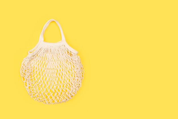 Una bolsa de malla de algodón sobre un fondo amarillo en una vista superior con espacio de copia