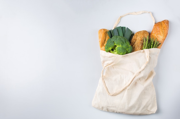 Foto bolsa de malla textil con productos, frutas y verduras. concepto reutilizable, reciclado, sin residuos, ecológico, sin plástico. copie el espacio, fondo coral blanqueado laico plano