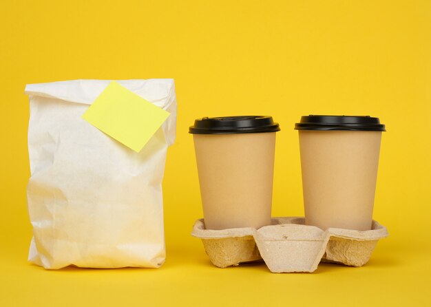 Bolsa de papel blanco, vasos desechables de papel marrón con una tapa de plástico en la bandeja