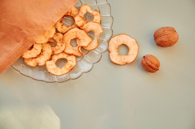 Bolsa de papel con chips de manzana en rodajas secas y bocadillos saludables de nueces en el plato Vista superior Nutrición adecuada concepto de comida saludable Foto de alta calidad