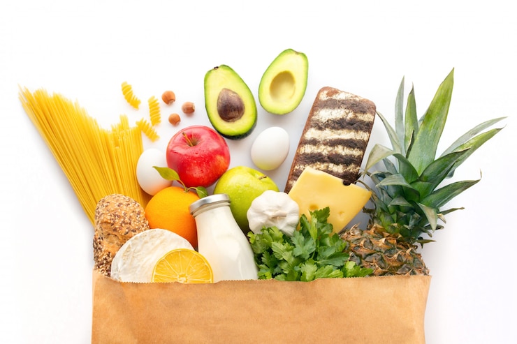 Foto una bolsa de papel completamente con varios productos saludables. fondo de alimentos saludables. concepto de comida de supermercado. leche, queso, frutas, verduras, aguacates y espagueti. compras en el supermercado. ingredientes.