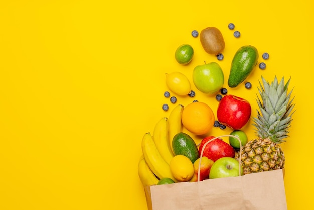 Bolsa de papel de compras llena de comida saludable en amarillo