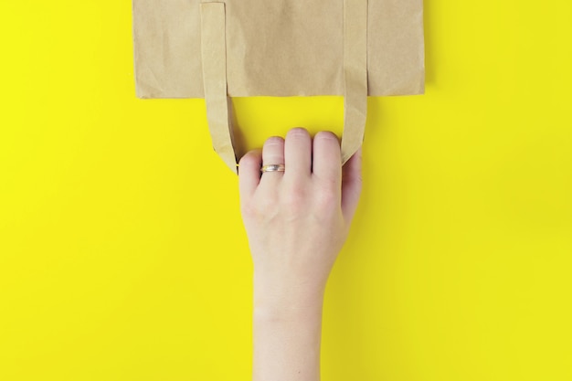 Bolsa de papel de compras sobre fondo amarillo con espacio de copia. foto plana de la bolsa volteada.