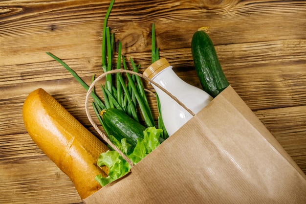 Bolsa de papel con diferentes alimentos en la mesa de madera Vista superior Concepto de compras de comestibles