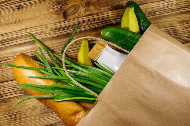 Bolsa de papel con diferentes alimentos en la mesa de madera Vista superior Concepto de compras de comestibles