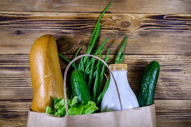 Bolsa de papel con diferentes alimentos de la tienda de comestibles en una mesa de madera Concepto de compras en el supermercado Vista superior