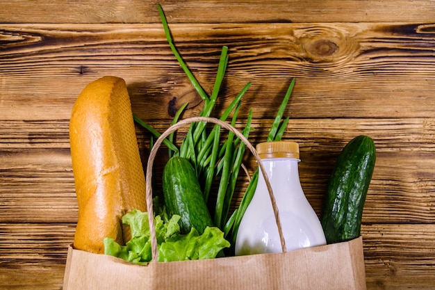 Bolsa de papel con diferentes alimentos de la tienda de comestibles en una mesa de madera Concepto de compras en el supermercado Vista superior