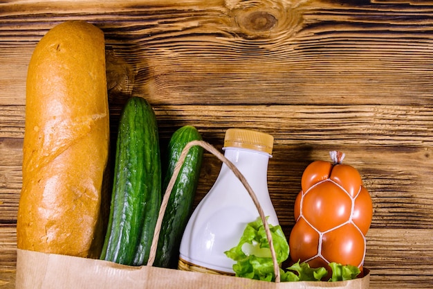 Bolsa de papel con diferentes alimentos de la tienda de comestibles en una mesa de madera Concepto de compras en el supermercado Vista superior