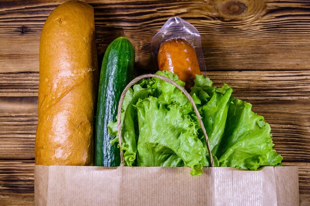 Bolsa de papel con diferentes alimentos de la tienda de comestibles en una mesa de madera Concepto de compras en el supermercado Vista superior