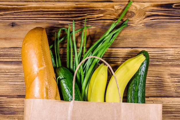 Bolsa de papel con diferentes alimentos de la tienda de comestibles en una mesa de madera Concepto de compras en el supermercado Vista superior