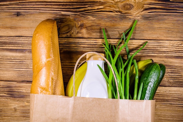 Bolsa de papel con diferentes alimentos de la tienda de comestibles en una mesa de madera Concepto de compras en el supermercado Vista superior