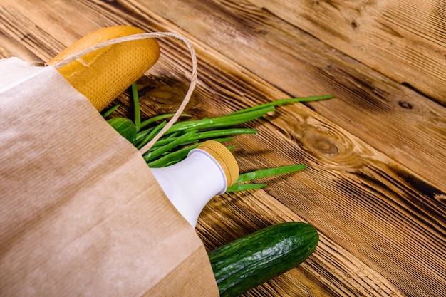 Bolsa de papel con diferentes alimentos de la tienda de comestibles en una mesa de madera Concepto de compras de supermercado