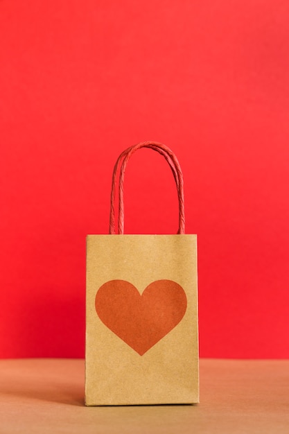 Bolsa de papel con estampado de corazón sobre fondo rojo.