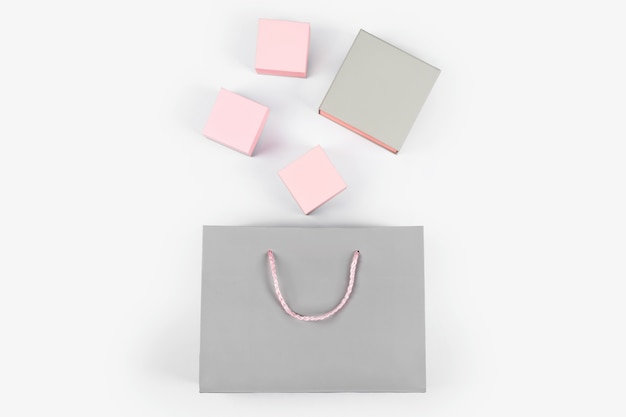 Bolsa de papel gris y cajas de regalo rosa sobre fondo claro. Espacio libre para texto. Concepto de compras, venta, sorpresa o regalo.