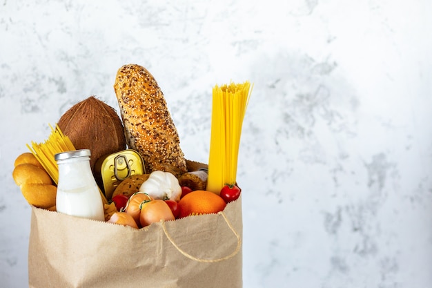 Bolsa de papel llena con comida sana. Fondo de comida sana. Concepto de comida de supermercado. Leche, queso, pan, frutas, verduras, aguacates, piña y espagueti. Compras en el supermercado. Entrega a domicilio