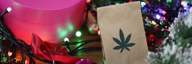 Bolsa de papel con marihuana se encuentra en la mesa entre oropel de año nuevo, regalos, guirnaldas