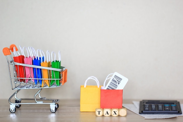 Bolsa de papel en modelo de carro en miniatura con calculadora en la mesa, concepto de compras y aumento de impuestos