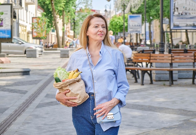 Una bolsa de papel de primer plano con verduras y frutas en manos femeninas