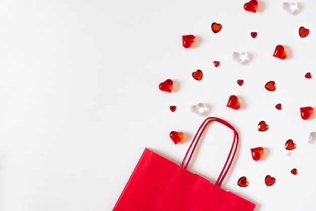 Una bolsa de papel roja con corazones al lado. Plantilla de tarjeta de felicitación con espacio de copia, diseño de texto, blogs de redes sociales.