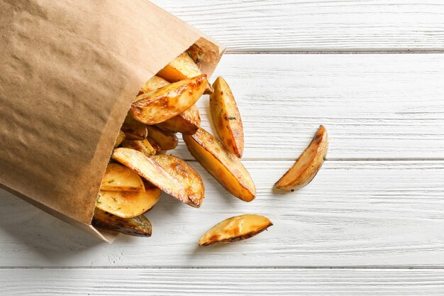 Bolsa de papel con sabrosos gajos de patata en la mesa