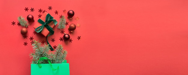 Bolsa de papel verde de Navidad con regalos y compras navideñas en rojo.