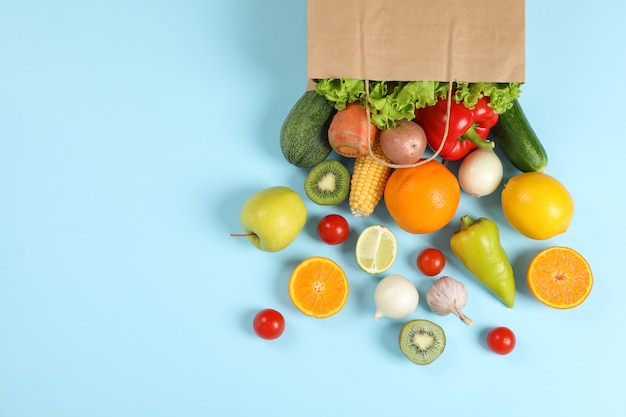 Bolsa de papel, verduras y frutas en el espacio azul para texto