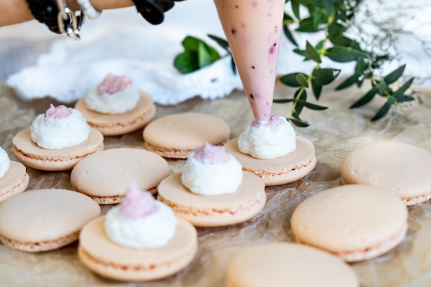 Foto de una bolsa de pastelería exprime la crema en la mitad de los macarrones enfoque selectivo clouse