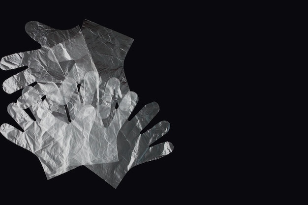 Bolsa de plástico con mangos guantes sobre un fondo negro Bolsa de plástico utilizada para el reciclaje Concepto de ecología contaminación del planeta con plástico celofán polietileno