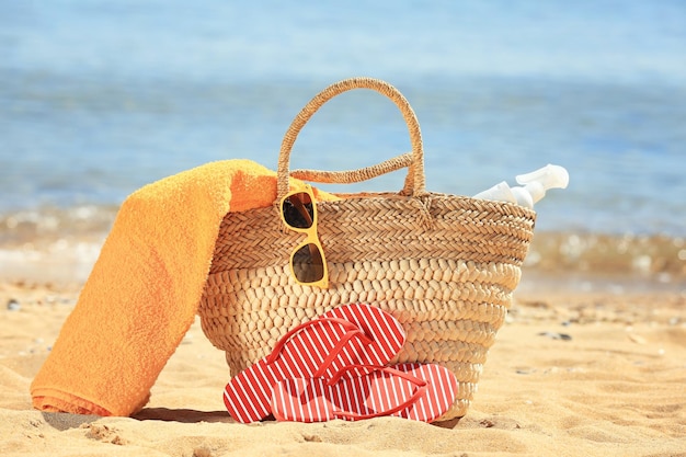 Bolsa de playa y accesorios en la arena a la orilla del mar Concepto de vacaciones