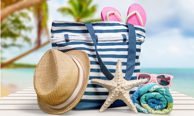 Bolsa de playa con sombrero y accesorios de playa en el fondo de la playa