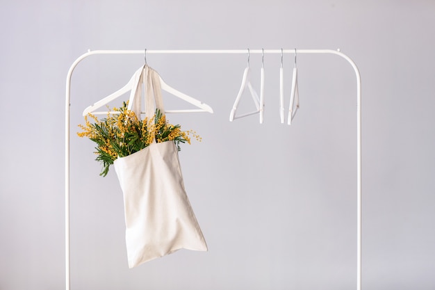 Bolsa con ramo de flores de mimosa colgando de una rejilla