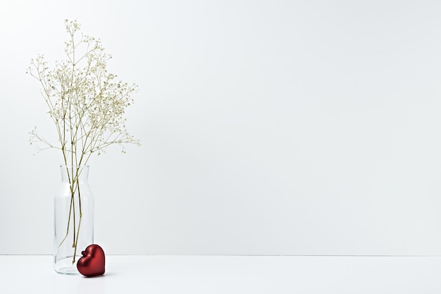 Bolsa de regalo y jarrón con flores secas en blanco.