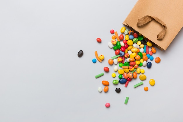 Bolsa de regalo de papel de compras en la esquina llena de dulces tradicionales variados cayendo sobre fondo de color con espacio de copia Concepto de venta de felices fiestas