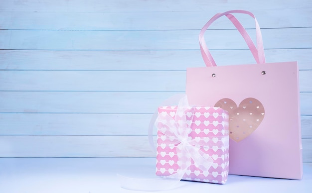 Foto bolsa de regalo rosa y caja de regalo rosa sobre la mesa.