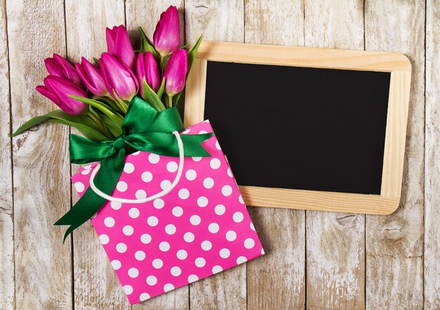 Foto bolsa rosa con flores rosas y una pizarra