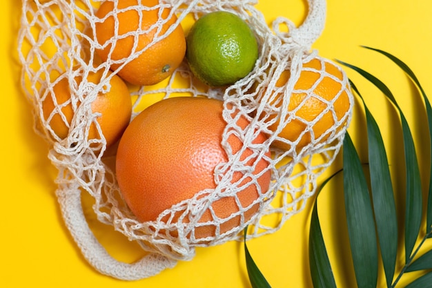 Una bolsa de supermercado con frutas tropicales se encuentra en un concepto de fondo amarillo de consumo responsable