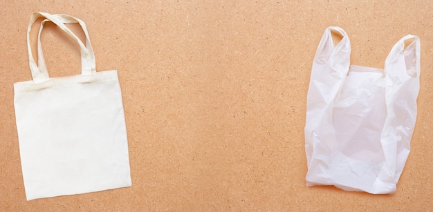 Bolsa de tela blanca con bolsa de plástico blanco sobre fondo de madera contrachapada.