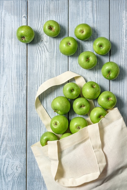 Bolsa de tela con manzanas verdes sobre una mesa de madera.Bolsa de compras de residuos cero con frutas.